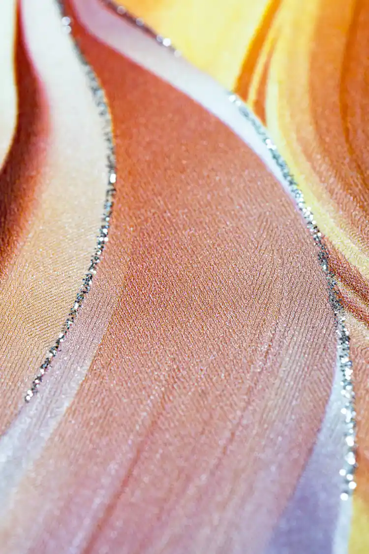 Extreme close-up macro of flowing orange and peach feather texture with silver glitter line on surface