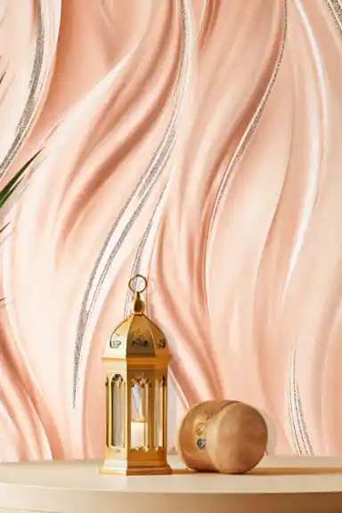 Installed wall view of peach flowing wave wallpaper with a gold lantern and decorative sphere on shelf