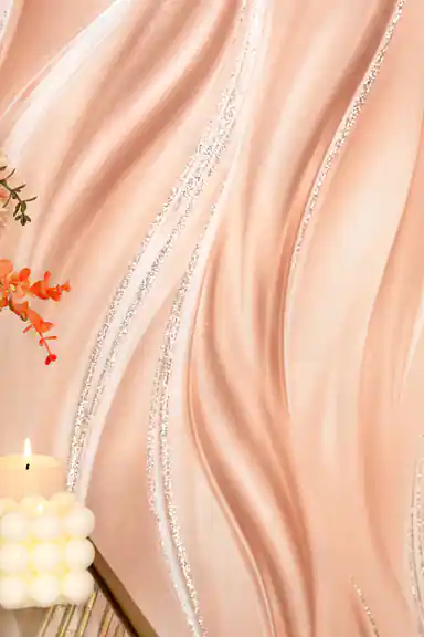 Close-up of peach silk wave wallpaper with silver glitter lines beside orange flowers and a candle