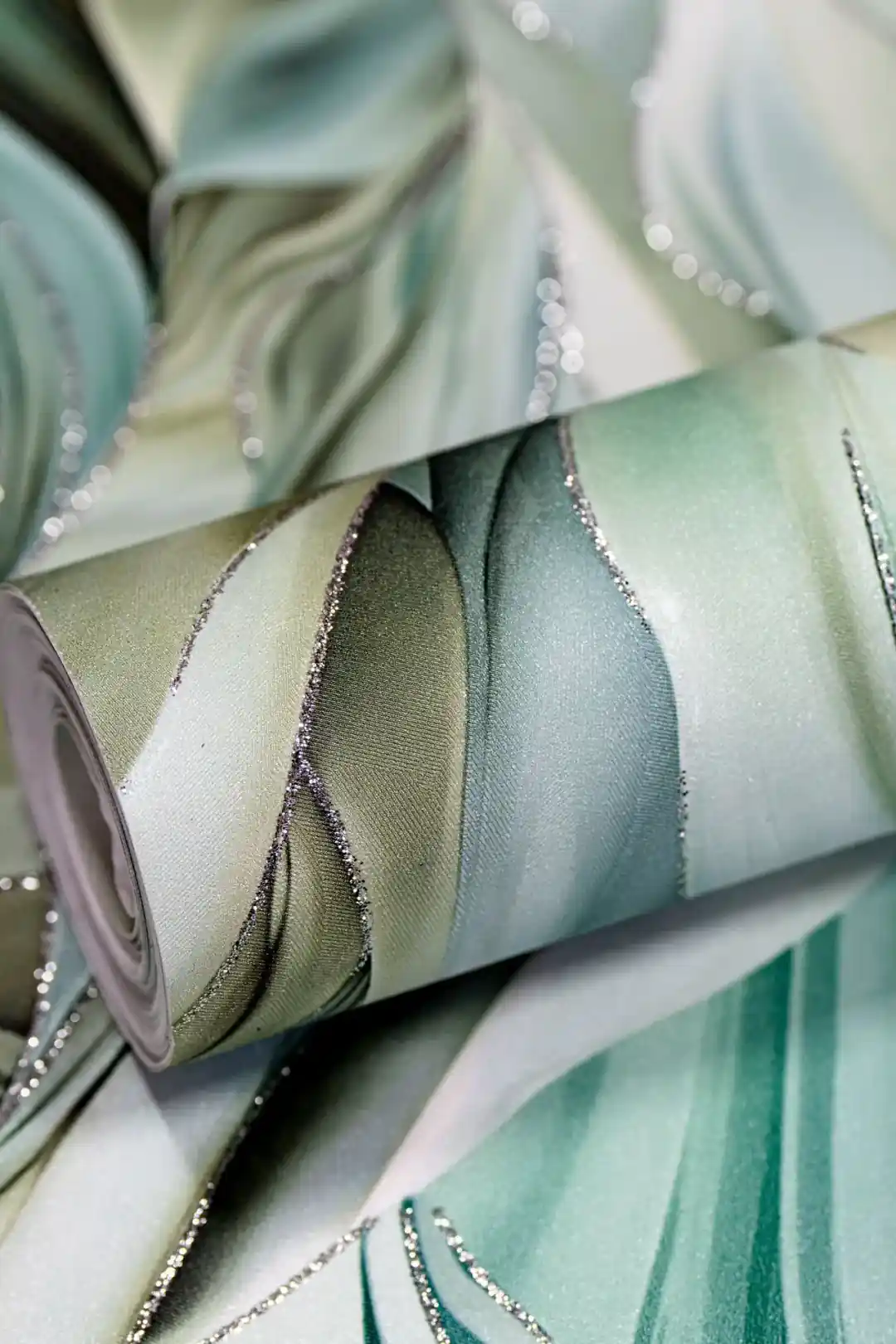 Rolled sage and olive green tropical leaf wallpaper showing flowing leaf design with glitter edge details