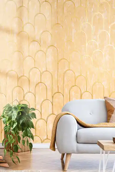 Gold art deco arch wallpaper installed in a living room with grey sofa, plant, and warm sunlight