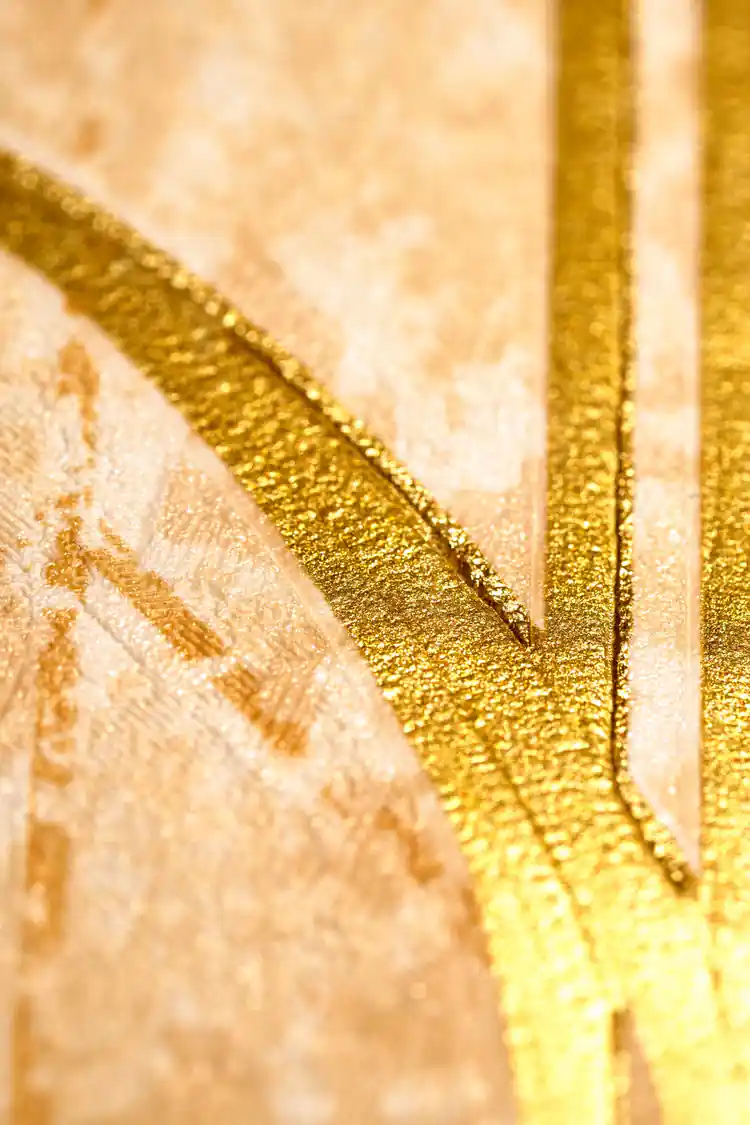 Extreme close-up macro of raised gold metallic line detail on textured gold art deco wallpaper surface