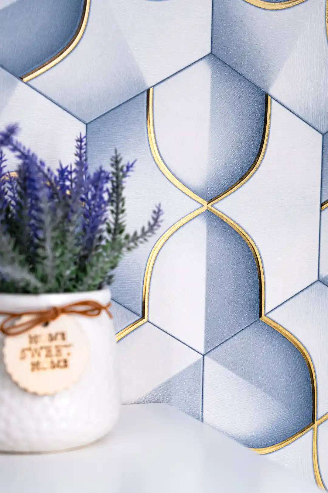 Close-up of blue and grey 3D hexagon petal wallpaper with gold outline accents beside a lavender plant