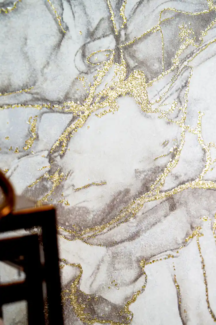 Close-up of grey marble wallpaper with sparkling metallic gold vein accents on an installed wall
