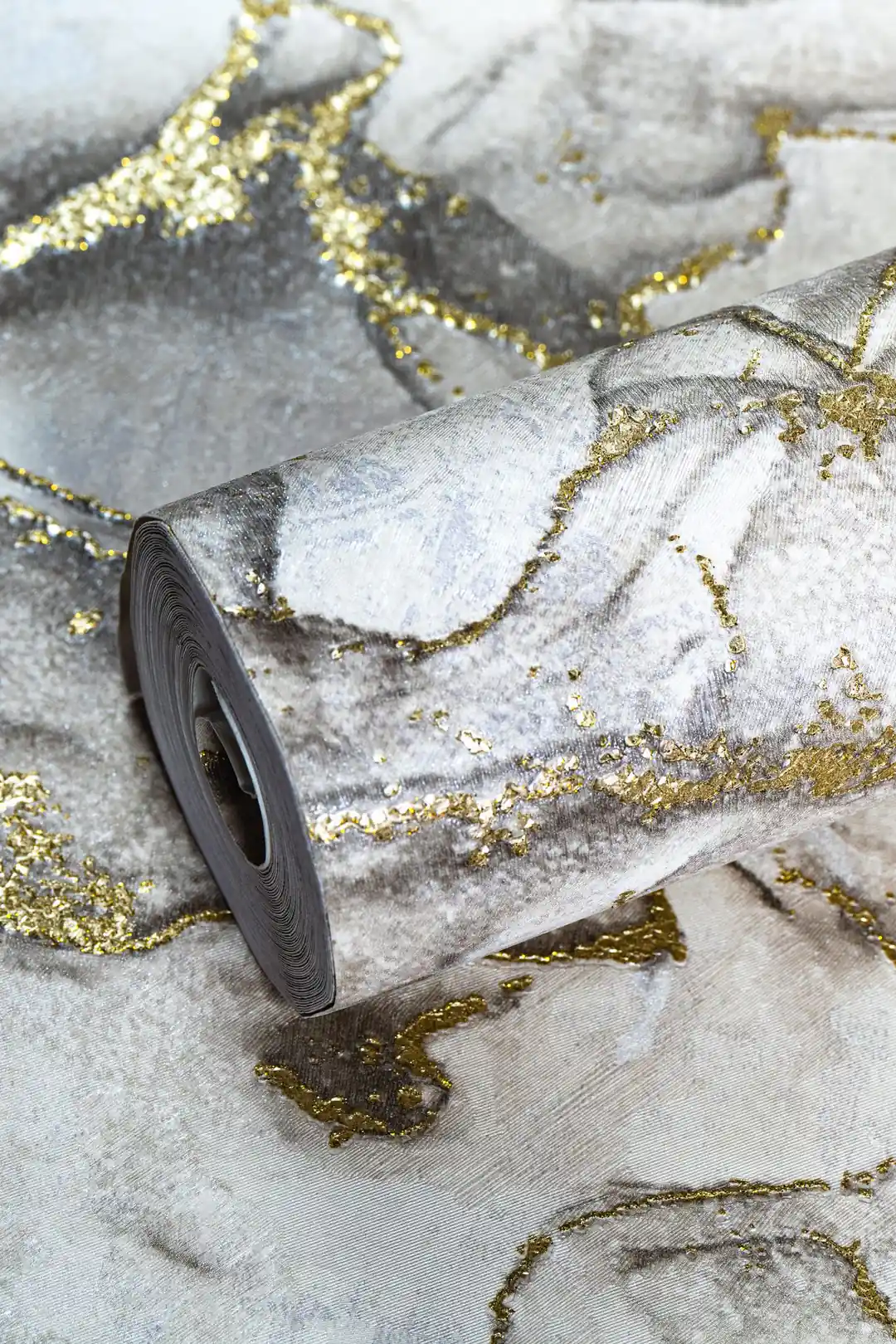 Full roll of grey marble wallpaper with gold glitter veining laid on the unrolled pattern