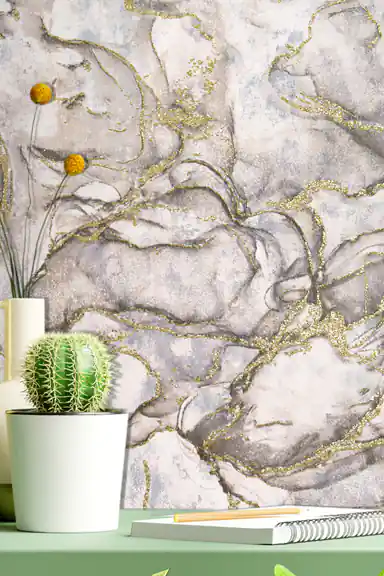 Styled vignette of grey marble wallpaper with gold veins behind a cactus and desk accessories