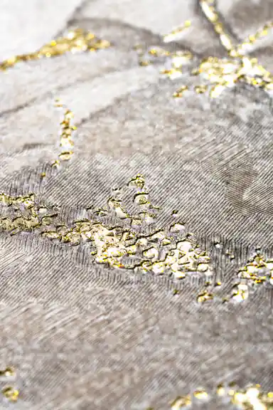 Extreme close-up of raised gold glitter particles on the textured grey marble wallpaper surface