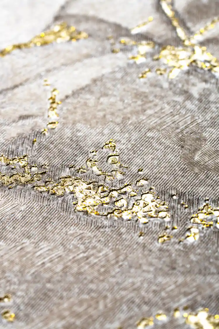 Extreme close-up of raised gold glitter particles on the textured grey marble wallpaper surface
