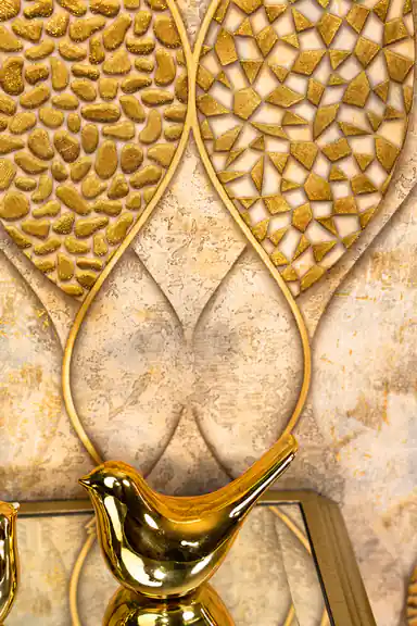 Detail shot of raised gold pebble and triangle mosaic textures within the wave-outlined leaf shapes with gold bird figurine in foreground