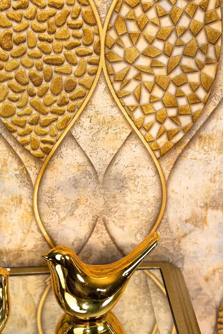 Detail shot of raised gold pebble and triangle mosaic textures within the wave-outlined leaf shapes with gold bird figurine in foreground