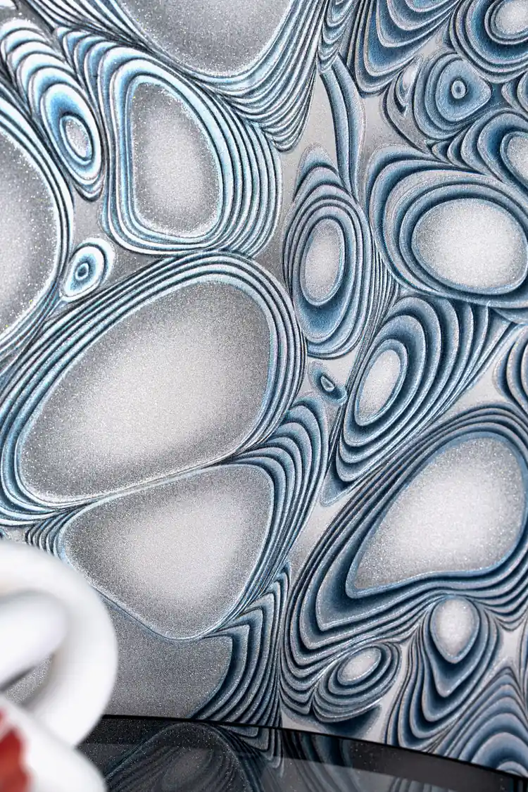 Close-up of blue molten steel curves with silver glitter accents on the installed wallpaper