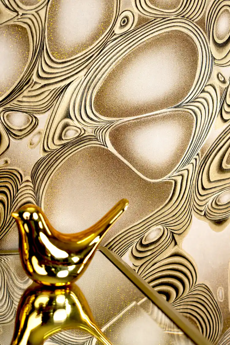 Close-up of bronze abstract molten pattern with a gold decorative bird figurine on shelf