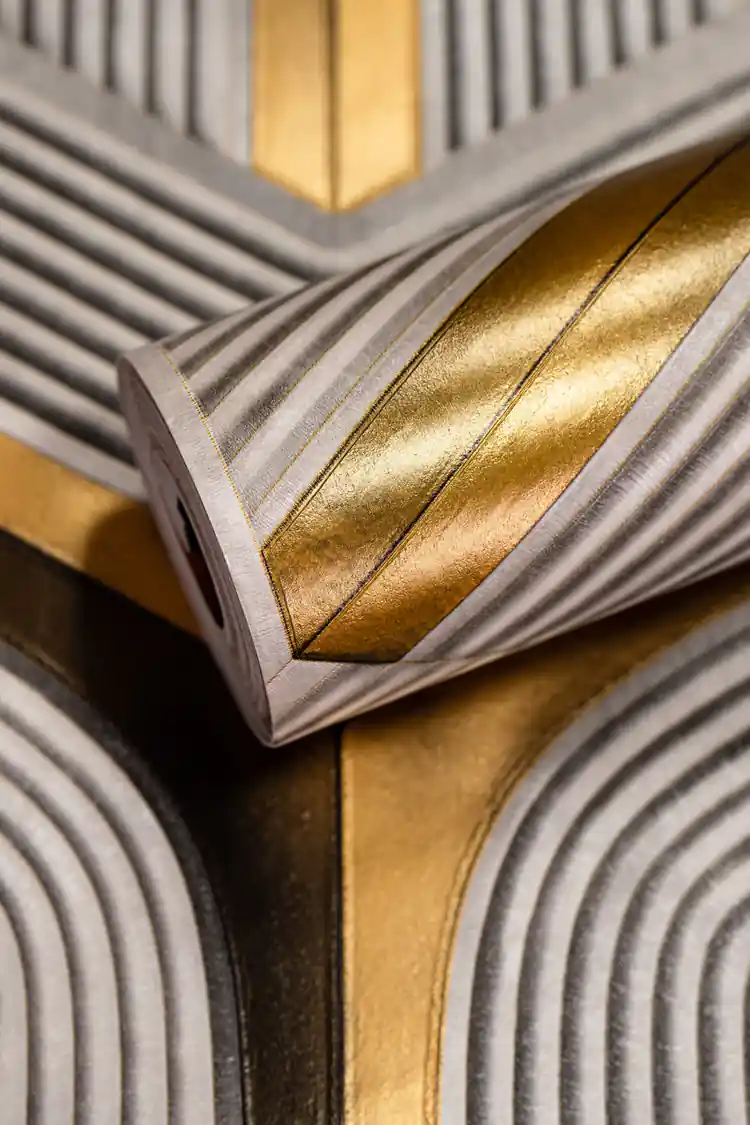 Rolled wallpaper with grey and gold 3D geometric maze pattern showing ribbed texture detail