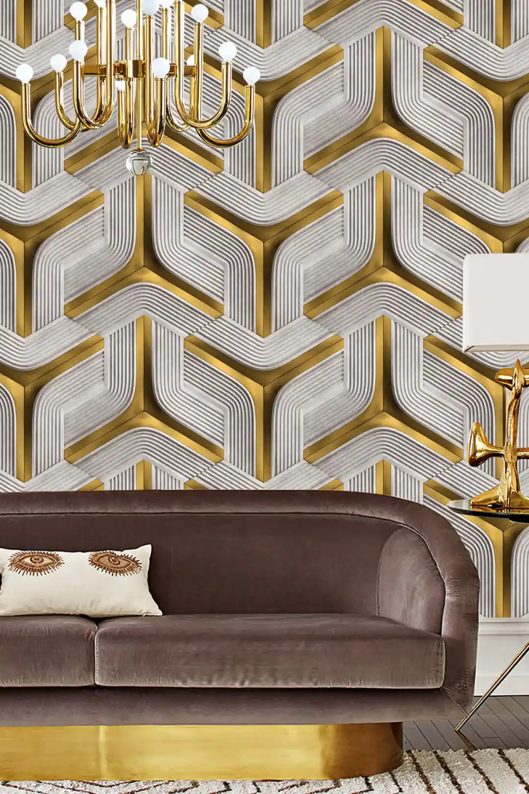 Elegant living room with gold and grey 3D geometric chevron wallpaper behind a velvet brown sofa and gold chandelier