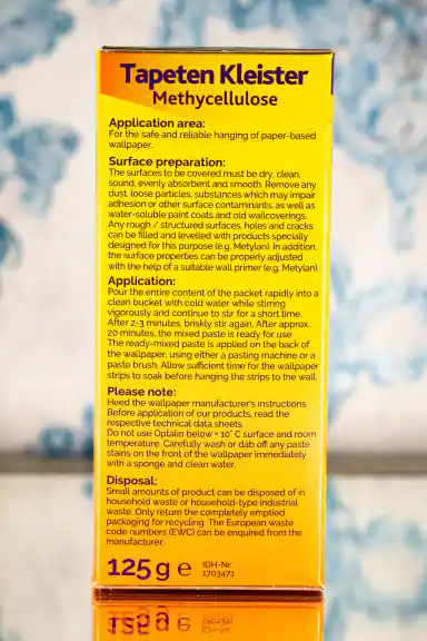 Side panel of Tapeten Kleister wallpaper glue box with application instructions, surface preparation steps, and 125g weight