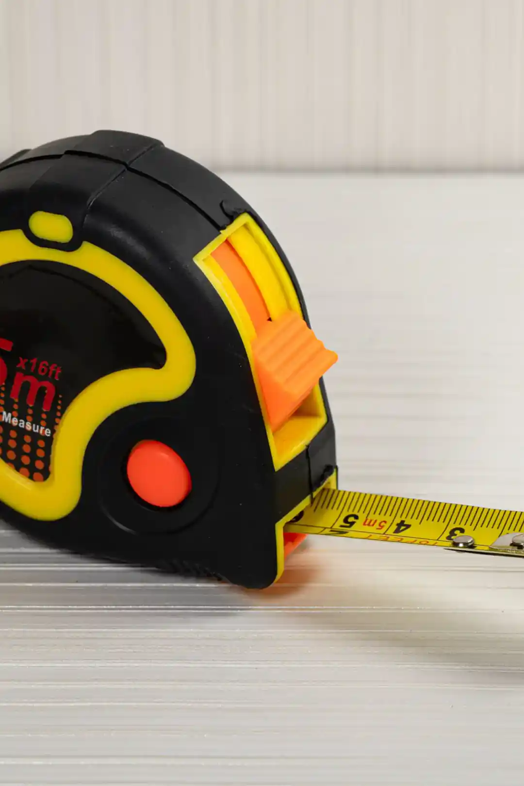 Side view of 5m measuring tape with yellow blade extended showing centimeter markings