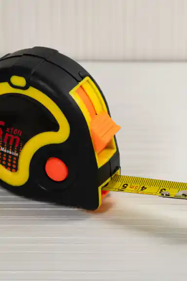 Side view of 5m measuring tape with yellow blade extended showing centimeter markings