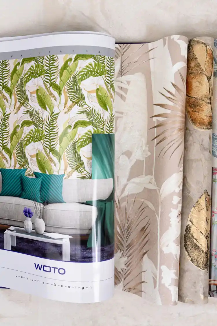 Open WOTO 1 book showing tropical green leaf and blush palm wallpaper designs with room scenes